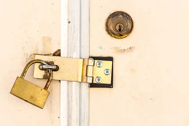 Old padlock lock on white door.