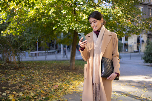 Business woman on the street using the phone and holding bag