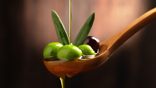 Olive oil being poured into wooden spoon