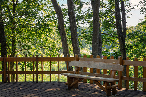 Handmade wooden bench in the recreation and viewing area in green trees background.