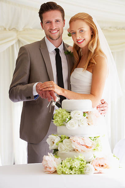 istock Bride And Groom Cutting Wedding Cake At Reception 180259015