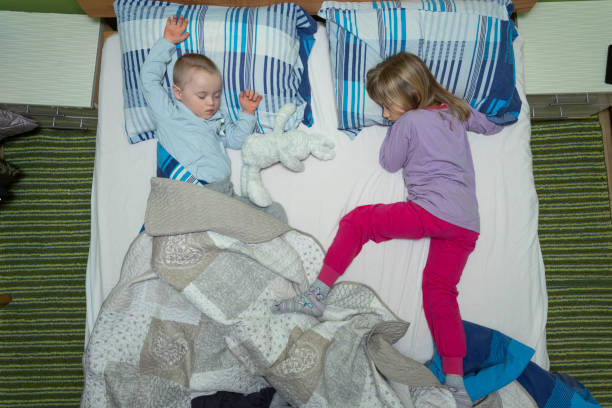 istock Two kids sleeping in parents bed. Shot from above. 1802600517