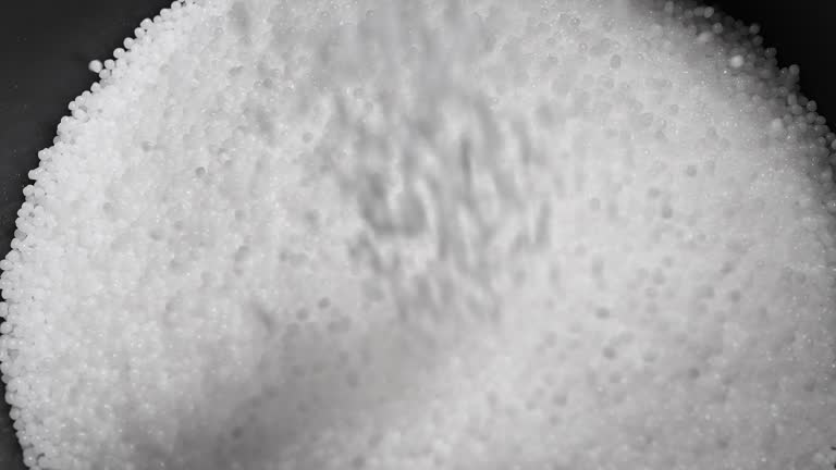 Filling the tank with plastic granules. The process of producing parts from polyethylene compound. White granules are poured into a container.