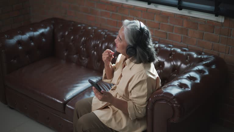 Happy Senior woman Listening Music via Smartphone Application and Headphones