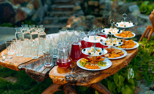 wooden buffet table with snack, appetizer and fruits decorated outdoor in summer day