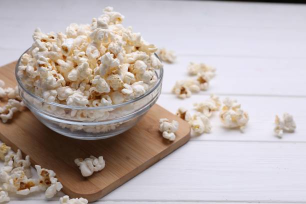 istock Tasty popcorn in bowl on white wooden table 1802627622