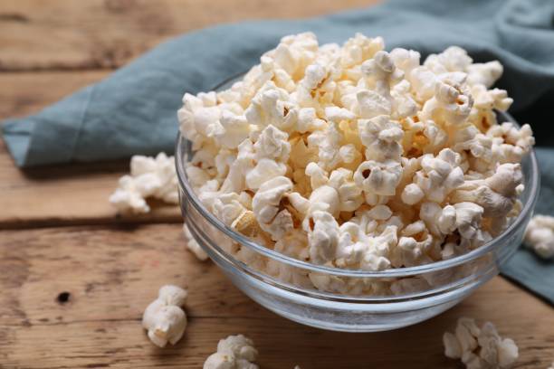 istock Tasty popcorn on wooden table, closeup view 1802628214