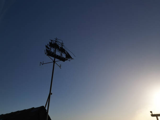 Sailing ship shaped silhouette weather vane at sunrise.