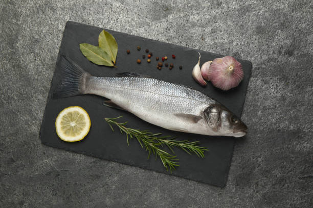 istock Sea bass fish and ingredients on grey table, top view 1802645285