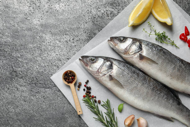 istock Sea bass fish and ingredients on grey table, above view. Space for text 1802646349