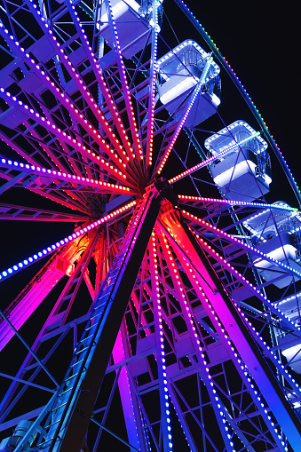 Ferris wheel also known as giant observation wheel, popular entertaining ride in amusement park, night scene low angle view with selective focus