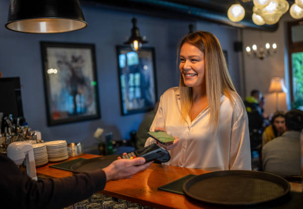 istock Young woman making a contactless payment at cafe using her cell phone 1802651682