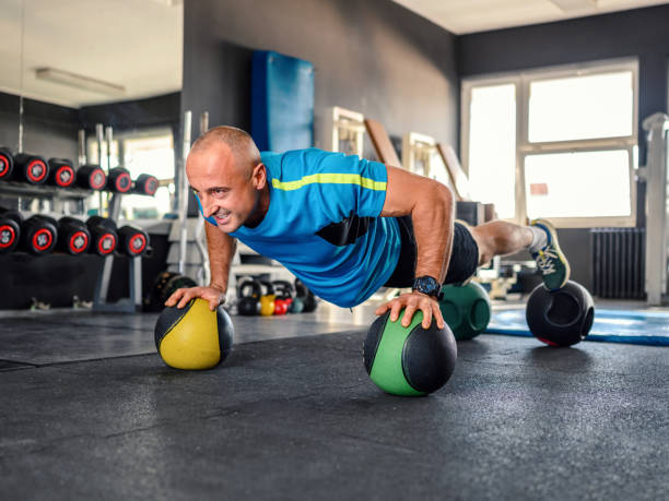 istock Confident young man using medicine ball while doing push-up exercises in gym 1802651683
