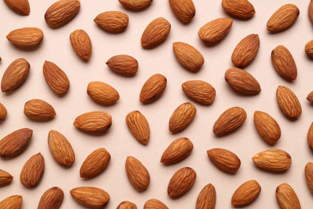 istock Delicious raw almonds on beige background, flat lay 1802672560