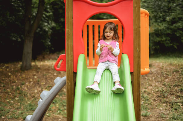 istock toddler girl using slide outdoors. 1802674720