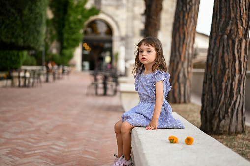 cute child sitting on a city street outdoors.