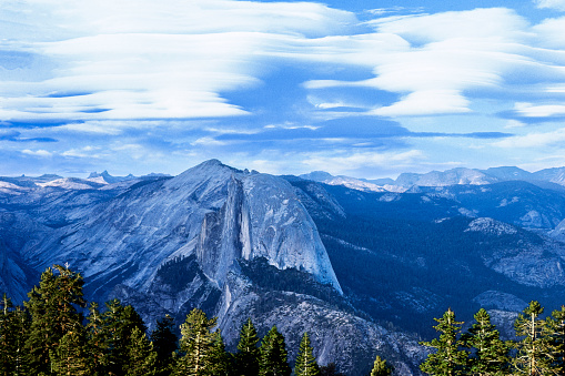 Springtime view of Half Dome from Glacier Point with distant snow covered peaks in background.\n\nTaken in Yosemite National Park, California, USA.