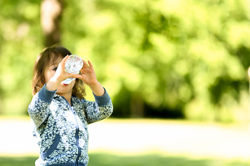 Child drinking water. Girl outdoors