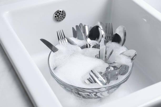 istock Washing silver spoons, forks and knives in kitchen sink with foam 1802705798