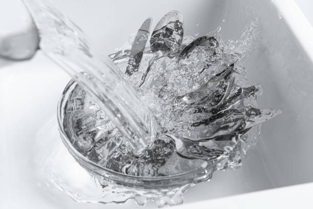 istock Washing silver kitchenware under stream of water in sink, above view 1802710210