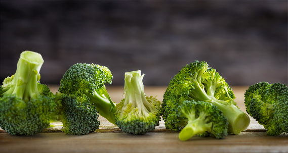 Fresh healthy green organic raw broccoli florets on wooden table
