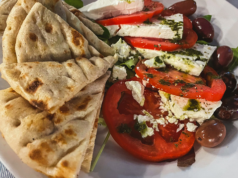 Dish with fresh tomatoes, olives, organic feta cheese and traditional Pita bread, Crete island, Greece