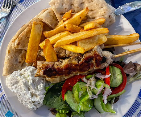 Dish with french fries, salad and chicken meat Souvlaki, traditional food of Greece