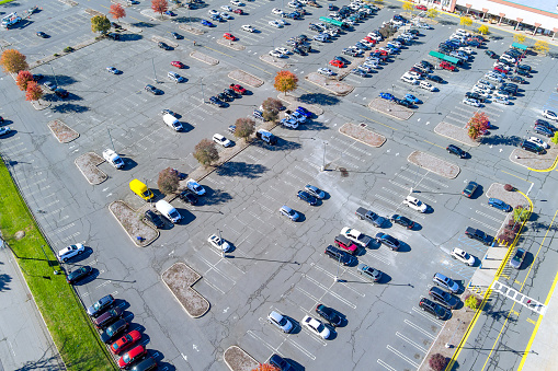 In state of New Jersey there is large asphalt parking lot for cars that is nearly empty.