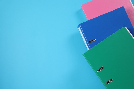 Many office folders on light blue background, flat lay. Space for text