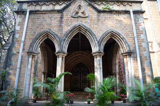 This image showcases the Afghan Church, also known as the Church of St. John the Evangelist, located in the Colaba area of Mumbai. Renowned for its Gothic Revival architecture, the church stands as a tribute to the soldiers of the First Afghan War of 1838. What stands out in the photograph are the church's impressive features, notably its towering spire and the exquisite stained glass windows that adorn the building. These windows, rich in colour and detail, cast a kaleidoscope of light within the church, adding to its solemn and reflective atmosphere. The image aims to capture both the architectural magnificence and the historical resonance of the Afghan Church, highlighting its role as a significant landmark in Mumbai's rich tapestry of history and culture.
