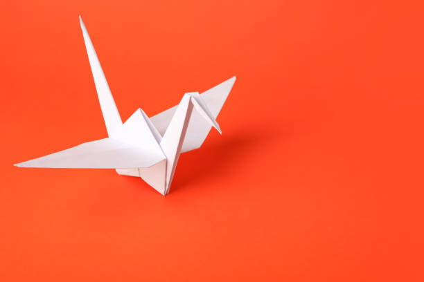 istock Origami art. Handmade paper crane on orange background, space for text 1802786490