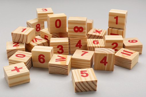 Wooden cubes with numbers and mathematical symbols on light background