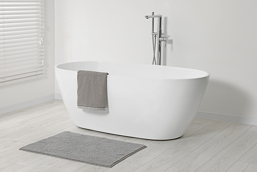 Stylish bathroom interior with ceramic tub and terry towel