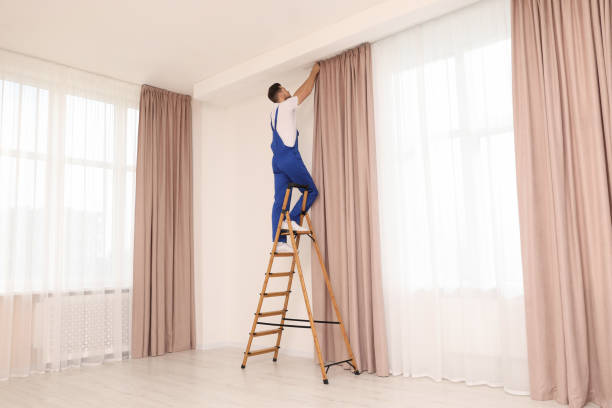 istock Worker in uniform hanging window curtain indoors 1802820474