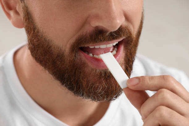 istock Man putting chewing gum into mouth on blurred background, closeup 1802822611