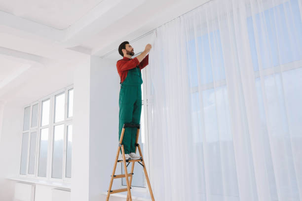 istock Worker in uniform hanging window curtain indoors, low angle view 1802824217