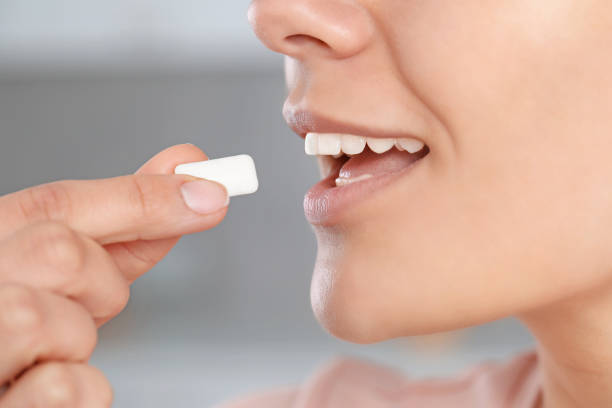istock Woman with chewing gum on blurred background, closeup 1802826987
