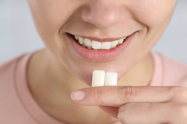 istock Woman with chewing gums on light background, closeup 1802828984