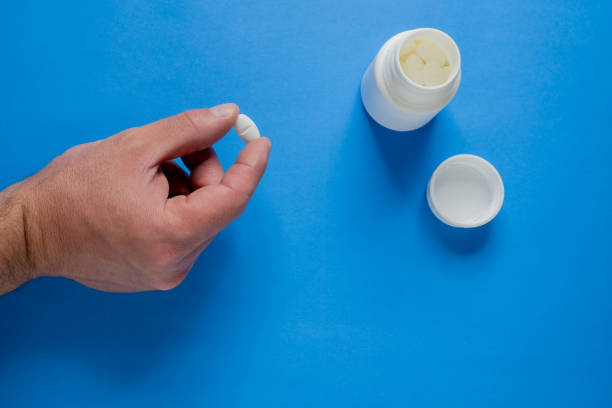 istock Fingers holding a white pill. 1802831843