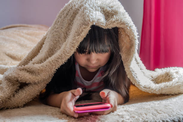 istock A child using a smartphone lying in bed, playing games, watching online videos, scrolling the screen. Children's screen addiction. Children's room. 1802832405