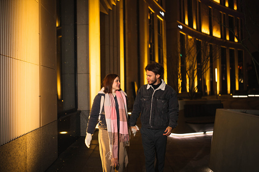 loving couple in winter clothes walks  the city in the evening, happy young people in cold weather.