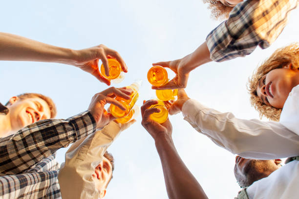 istock group of multiracial young people clink beer bottles outdoors, interracial students celebrating toast and relaxing 1802836883