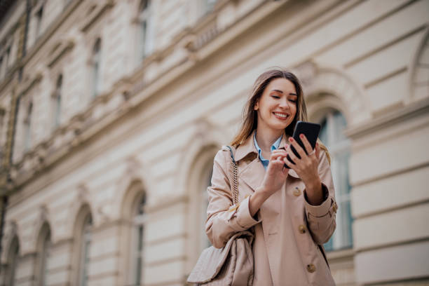 istock Smiling woman using mobile phone while outside on a city street 1802842074