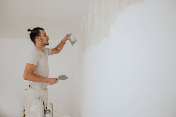 istock A builder is on ladder is skim coating and plastering walls. 1802846196