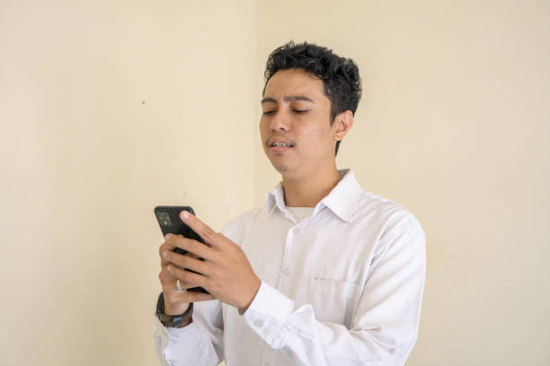 istock Indonesian man wear white clothes texting on smartphone. 1802859983