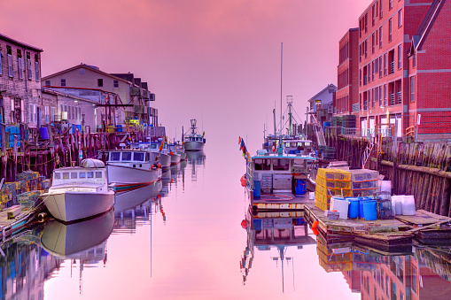 Oranges and pinks highlight all the boats, water and sky in Oceanside Harbor, near Carlsbad, California in Southern California.