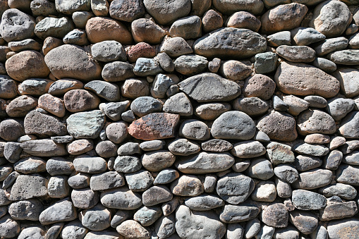 Sturdy rustic wall constructed from a diverse stones . Background of stone wall texture
