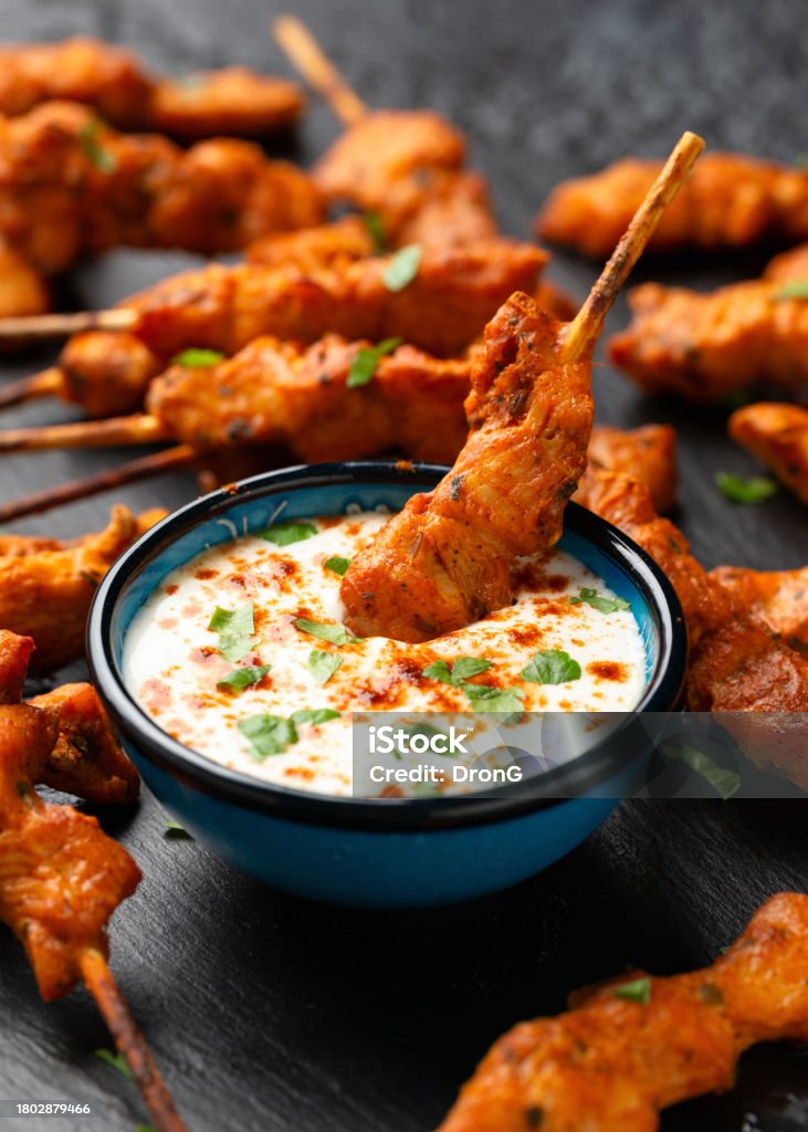 Grilled chicken fillet on skewers with white sauce on rustic stone board Grilled chicken fillet on skewers with white sauce on rustic stone board. Color Image Stock Photo