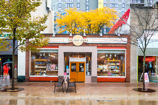 October 26, 2023 - Madison, Wisconsin, USA: The Soap Opera store on State Street in rain with reflections and autumn foliage