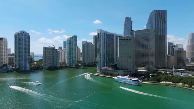 Amazing drone view of modern skyscrapers and buildings located near coastline of ocean on sunny day. Sailboats in water moving along Brickell in Miami, Florida